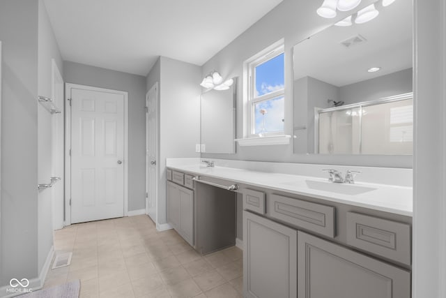 full bath with double vanity, visible vents, a shower stall, a sink, and baseboards