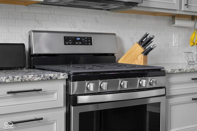 details with stainless steel range with gas stovetop, light stone countertops, and decorative backsplash