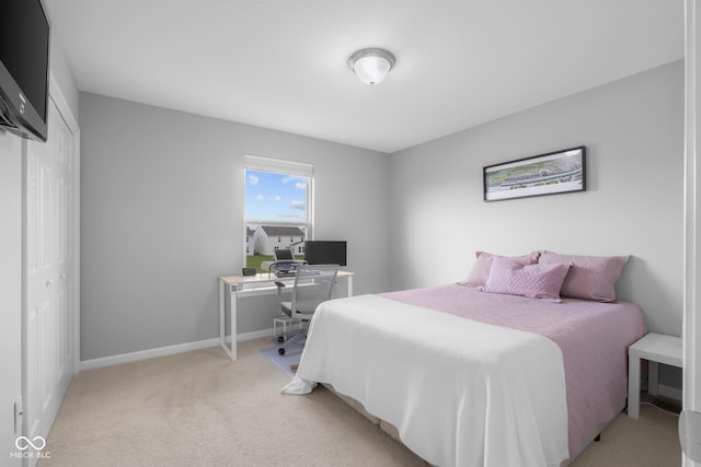 bedroom featuring baseboards, light carpet, and a closet
