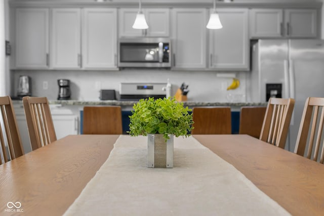 kitchen featuring light stone countertops, hanging light fixtures, and stainless steel appliances