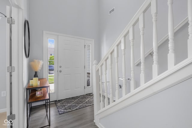 entryway with visible vents, stairs, a towering ceiling, and wood finished floors