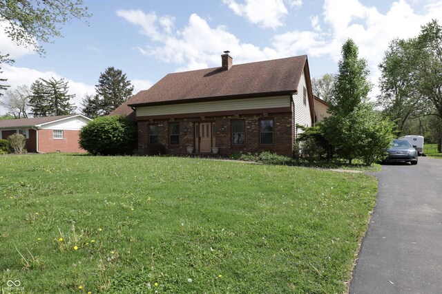 9903 E Raymond St, Indianapolis, IN 46239 - view of property exterior featuring a lawn, a chimney, and brick siding