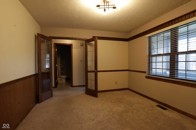 9903 E Raymond St, Indianapolis, IN 46239 - unfurnished room featuring visible vents, a textured ceiling, french doors, and light colored carpet
