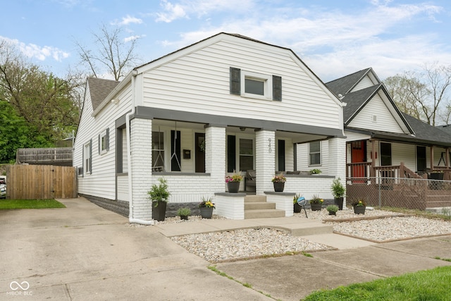 view of front of home featuring brick siding, a shingled roof, fence, and covered porch