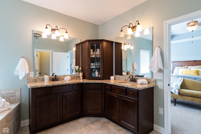 full bath with ensuite bath, a chandelier, double vanity, and a relaxing tiled tub