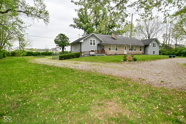 back of property featuring a chimney, a yard, and driveway