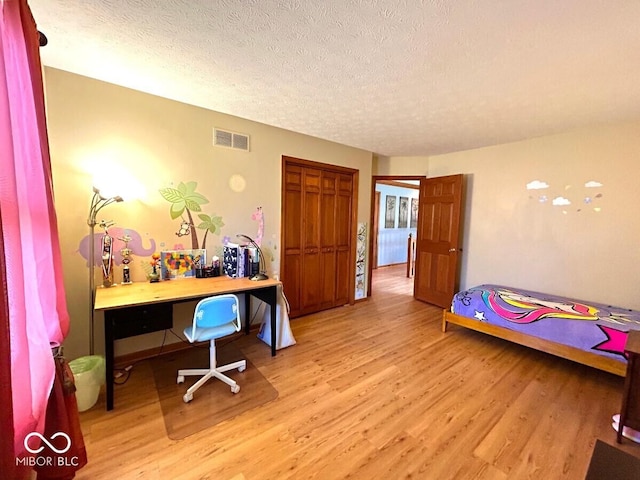 bedroom featuring visible vents, a textured ceiling, and light wood finished floors