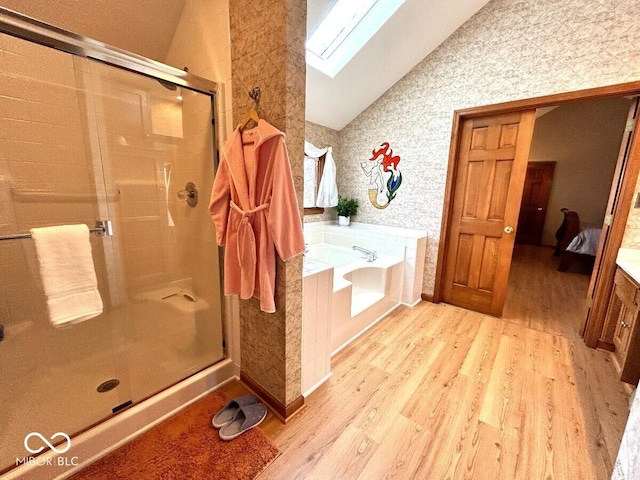 full bath with vaulted ceiling with skylight, wallpapered walls, a shower stall, wood finished floors, and a garden tub