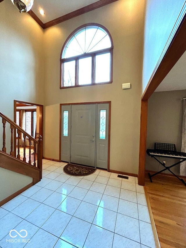 entryway with a high ceiling, ornamental molding, baseboards, and a wealth of natural light