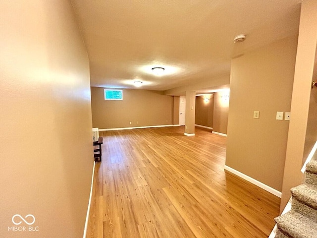 empty room featuring stairway, baseboards, and light wood-type flooring