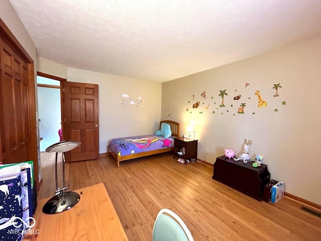 bedroom featuring baseboards, light wood-style flooring, and visible vents