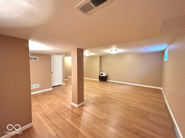 finished below grade area featuring visible vents, light wood finished floors, and baseboards
