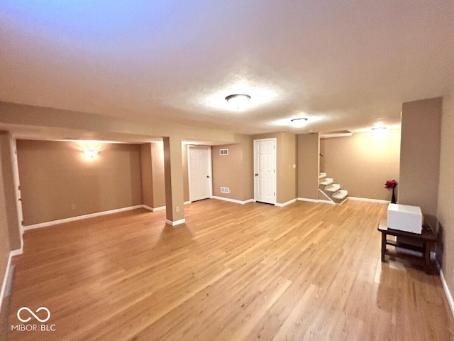 finished basement with baseboards, stairs, wood finished floors, and visible vents