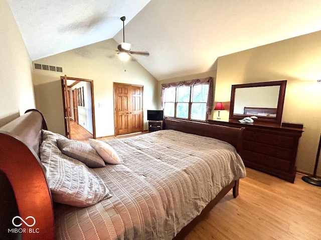 bedroom with a ceiling fan, high vaulted ceiling, visible vents, and wood finished floors