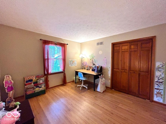 office featuring visible vents, a textured ceiling, baseboards, and light wood-type flooring