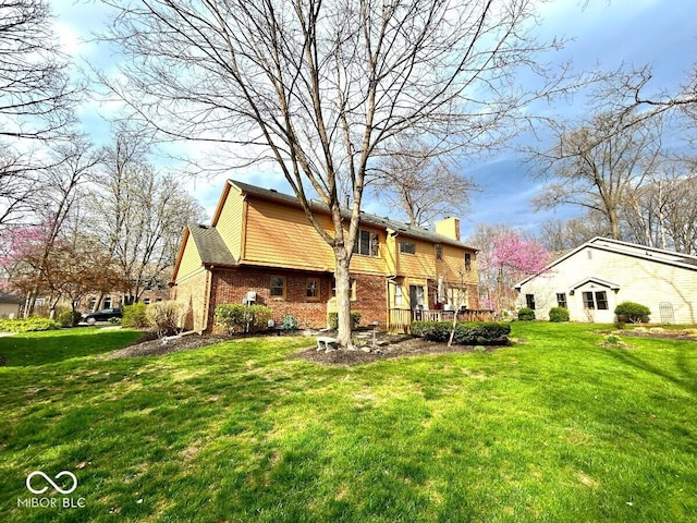 back of house with a lawn, a chimney, and brick siding
