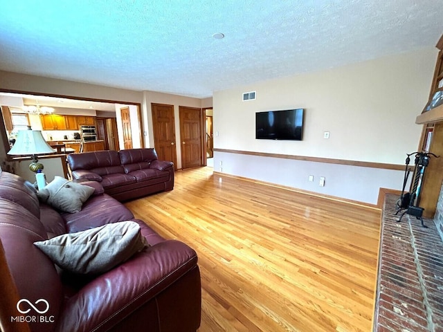 living room with visible vents, a textured ceiling, and light wood-style flooring