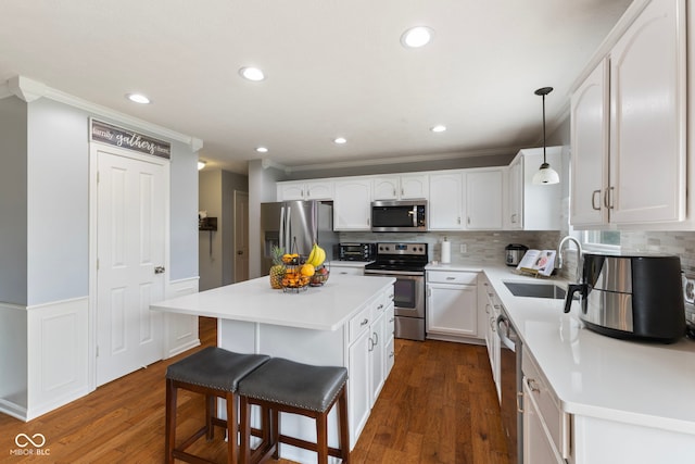 kitchen with ornamental molding, a kitchen bar, white cabinetry, tasteful backsplash, and stainless steel appliances