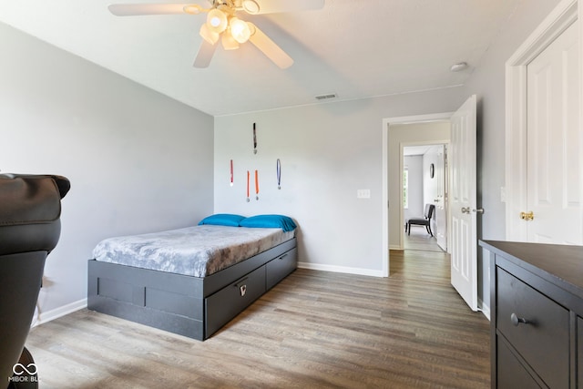 bedroom featuring visible vents, a ceiling fan, baseboards, and wood finished floors