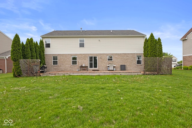 back of house with a lawn and brick siding