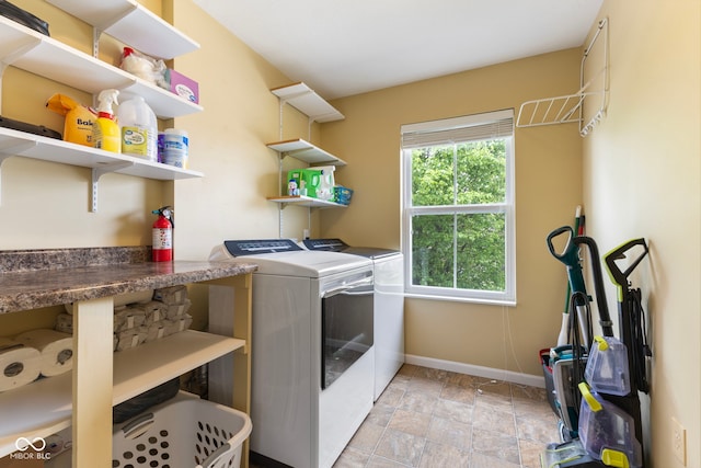 clothes washing area featuring washer and dryer, laundry area, stone finish floor, and baseboards
