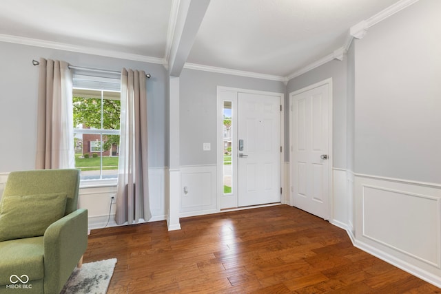 entrance foyer with ornamental molding, a decorative wall, wood finished floors, and a wainscoted wall