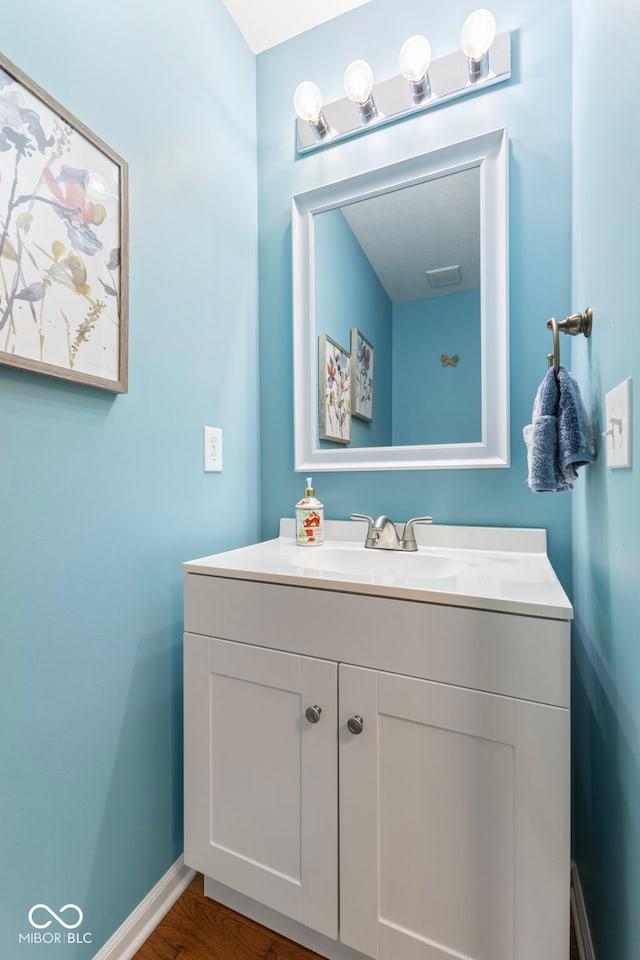 bathroom with baseboards, wood finished floors, and vanity