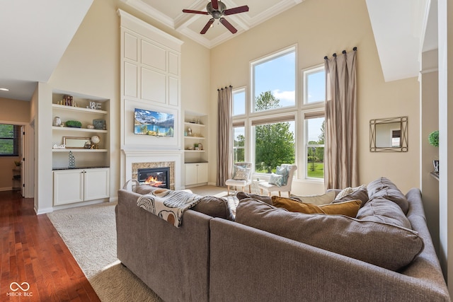 living room featuring a healthy amount of sunlight, a high ceiling, a glass covered fireplace, and ceiling fan