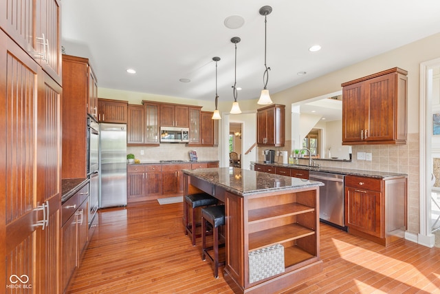 kitchen with a kitchen island, appliances with stainless steel finishes, tasteful backsplash, open shelves, and light wood-style floors