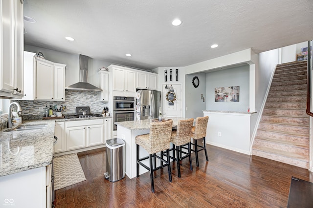 14584 Hinton Dr, Fishers, IN 46037 - kitchen featuring appliances with stainless steel finishes, a sink, wall chimney range hood, dark wood-style flooring, and white cabinets