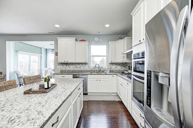 14584 Hinton Dr, Fishers, IN 46037 - kitchen with stainless steel appliances, a sink, dark wood-style flooring, light stone countertops, and decorative backsplash