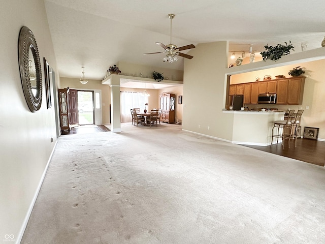 unfurnished living room featuring baseboards, ceiling fan, high vaulted ceiling, and light colored carpet