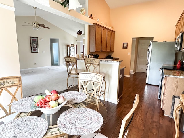dining area with baseboards, ceiling fan, and high vaulted ceiling