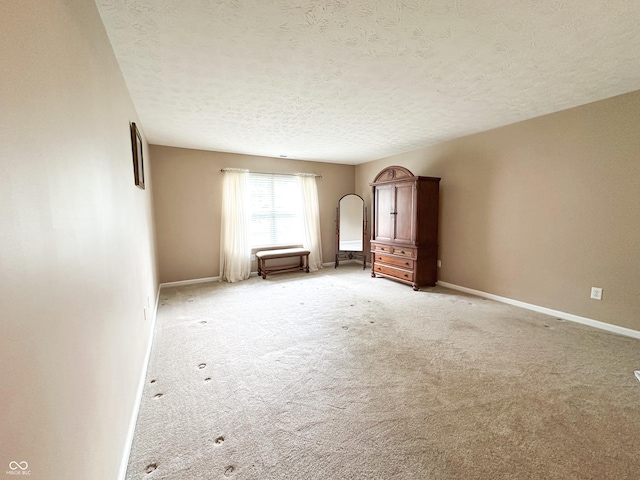 empty room with baseboards, light carpet, and a textured ceiling
