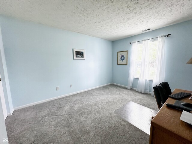 carpeted home office with baseboards, a textured ceiling, and visible vents