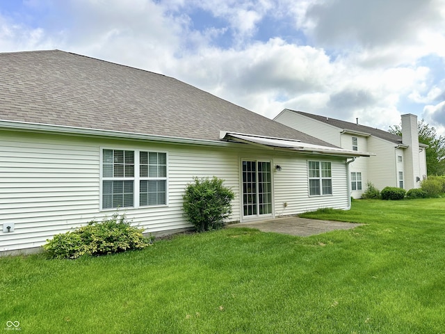 rear view of house featuring a lawn, a shingled roof, and a patio area