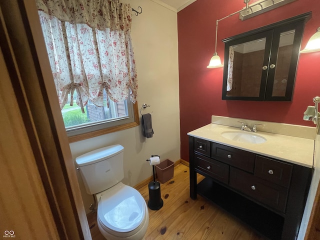 half bathroom with vanity, baseboards, wood finished floors, and toilet
