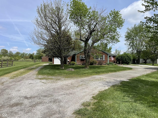 view of front facade with fence, dirt driveway, and a front yard