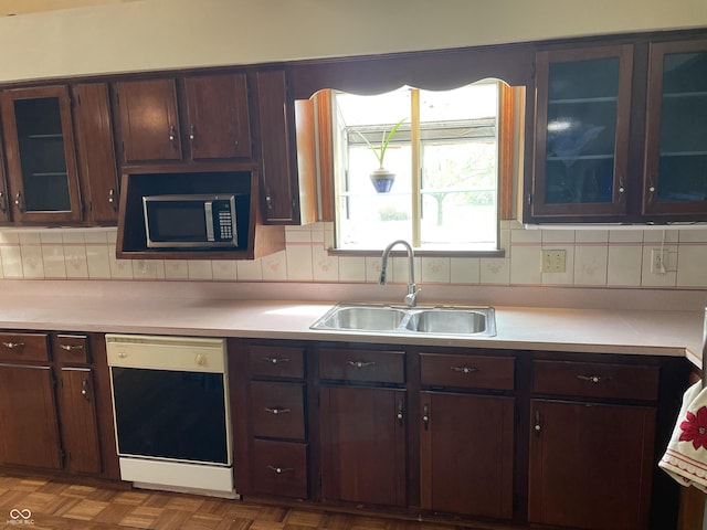 kitchen with light countertops, stainless steel microwave, a sink, and dishwasher