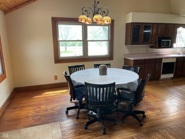 dining space with baseboards, vaulted ceiling, hardwood / wood-style flooring, and a wealth of natural light