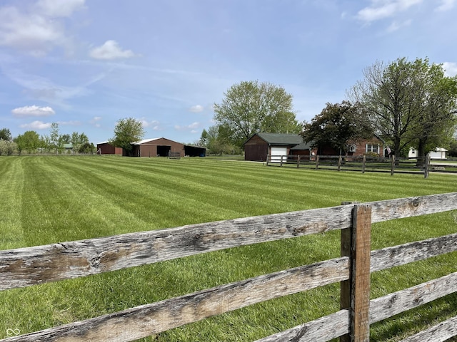 view of yard featuring fence, a pole building, an outbuilding, and a rural view