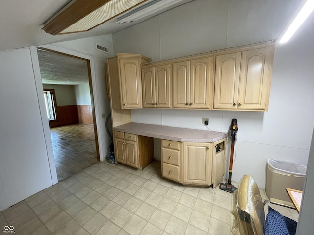 interior space with light tile patterned floors, wainscoting, cabinet space, and visible vents