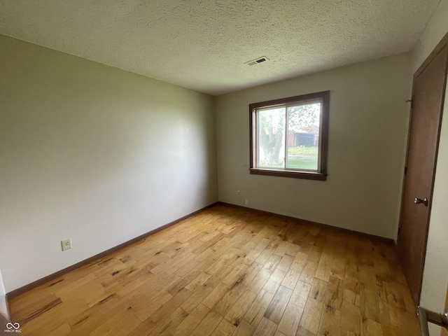 unfurnished bedroom featuring baseboards, a textured ceiling, visible vents, and light wood-style flooring