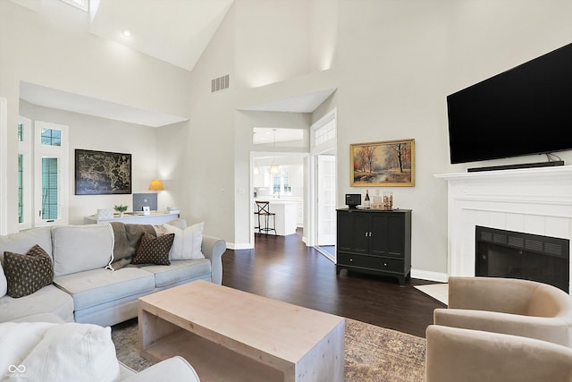 living area with high vaulted ceiling, baseboards, dark wood-type flooring, and visible vents