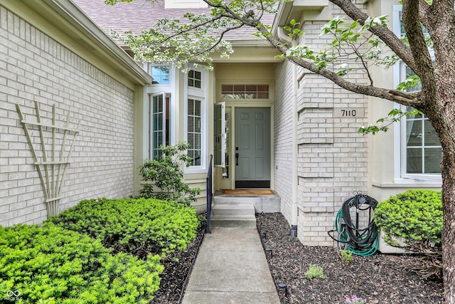 property entrance featuring brick siding and roof with shingles