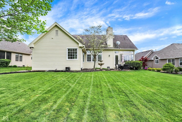 back of property with a lawn, a chimney, and a patio