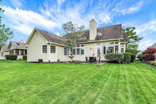 back of property featuring a patio, a yard, and a chimney