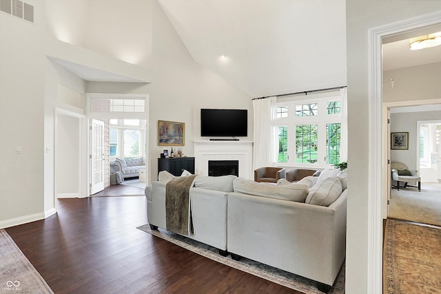 living area with high vaulted ceiling, a wealth of natural light, a fireplace, and visible vents
