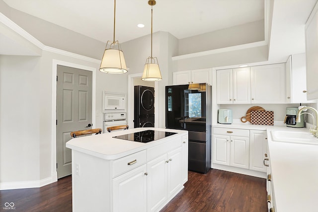 kitchen featuring stacked washer and dryer, white appliances, a center island, dark wood-type flooring, and a sink