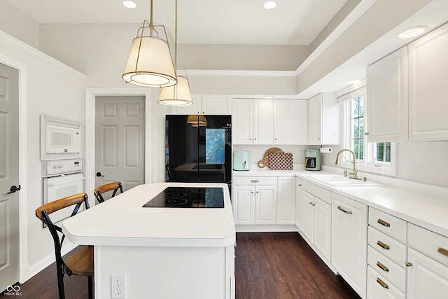 kitchen featuring a sink, black appliances, a kitchen bar, and white cabinetry